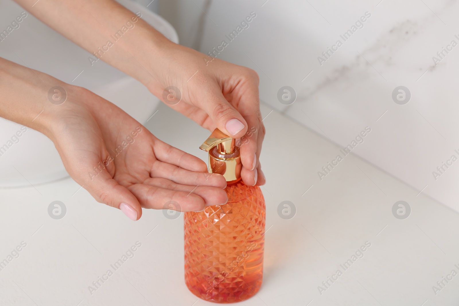 Photo of Woman using liquid soap dispenser at counter, closeup