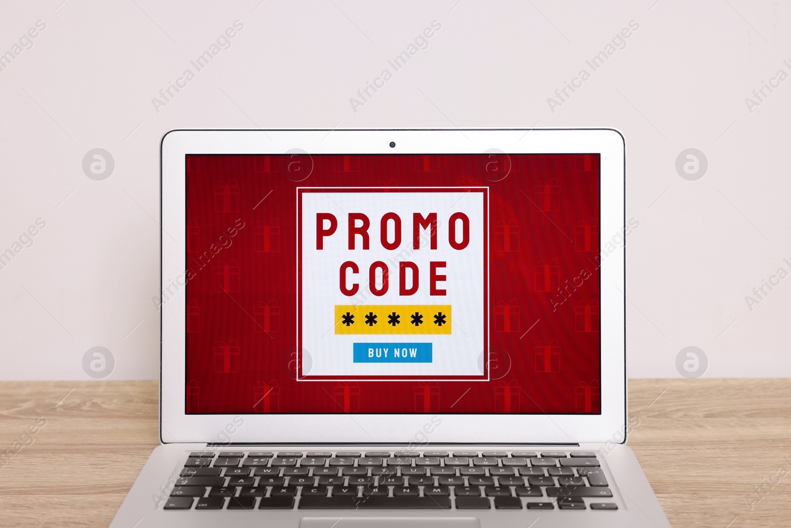 Photo of Laptop with activated promo code on wooden table near white wall