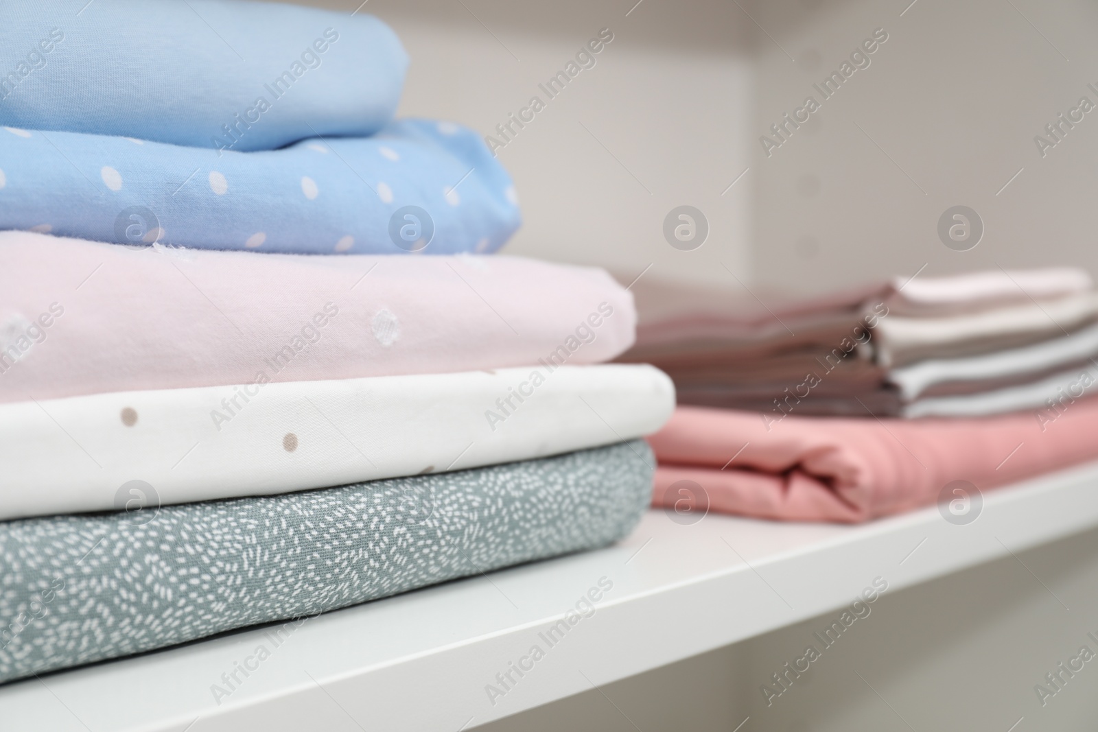 Photo of Bed linens on shelf in shop, closeup. Space for text