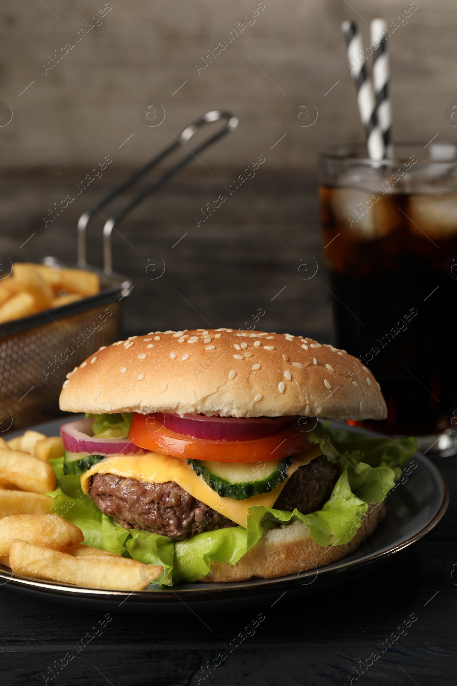 Photo of Delicious burger, soda drink and french fries served on black table, closeup