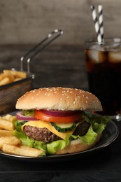 Delicious burger, soda drink and french fries served on black table, closeup