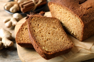 Photo of Fresh sliced gingerbread cake on wooden cutting board, closeup