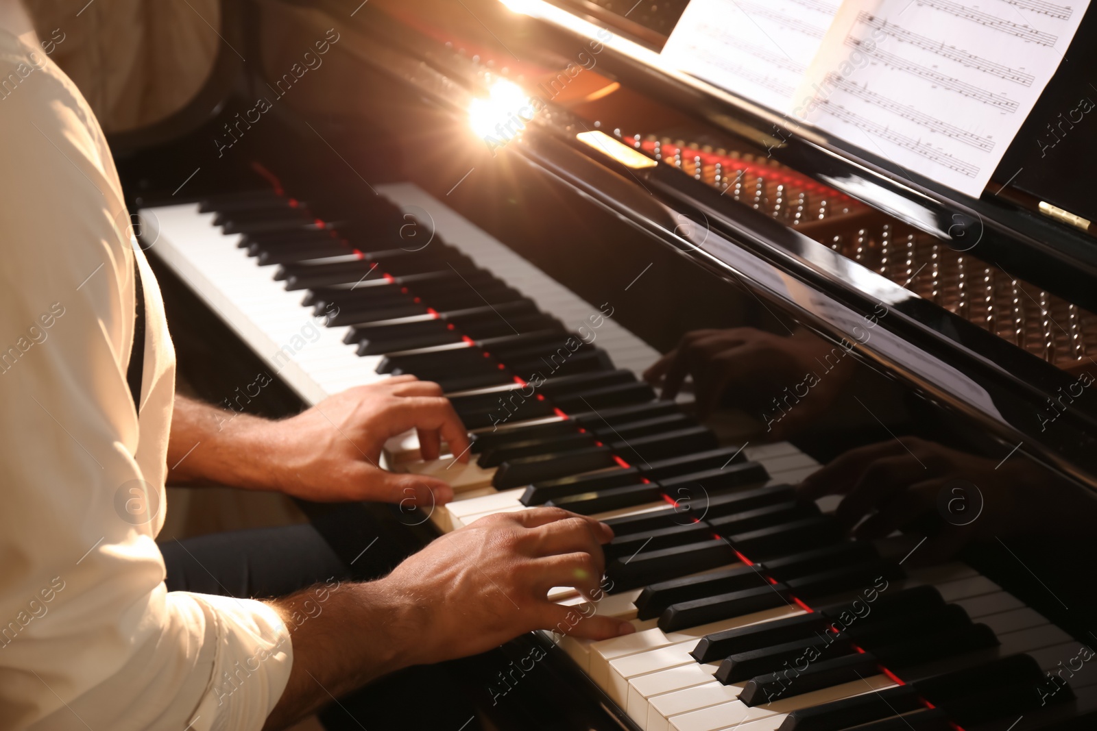 Photo of Man playing piano indoors, closeup. Talented musician