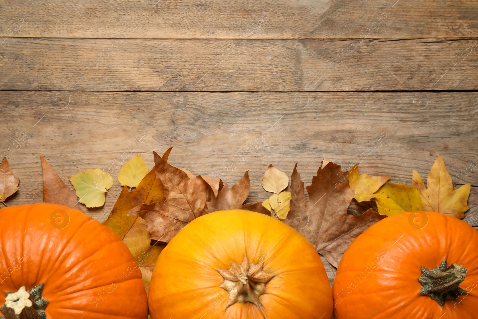 Photo of Flat lay composition with pumpkins and autumn leaves on wooden table. Space for text