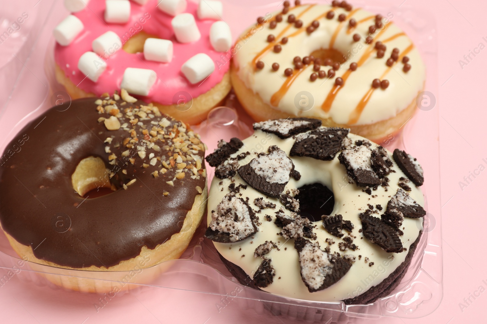 Photo of Box of delicious donuts on pink background, closeup