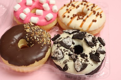 Box of delicious donuts on pink background, closeup