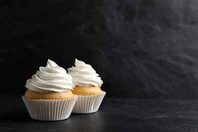 Photo of Delicious cupcakes with cream on black table. Space for text
