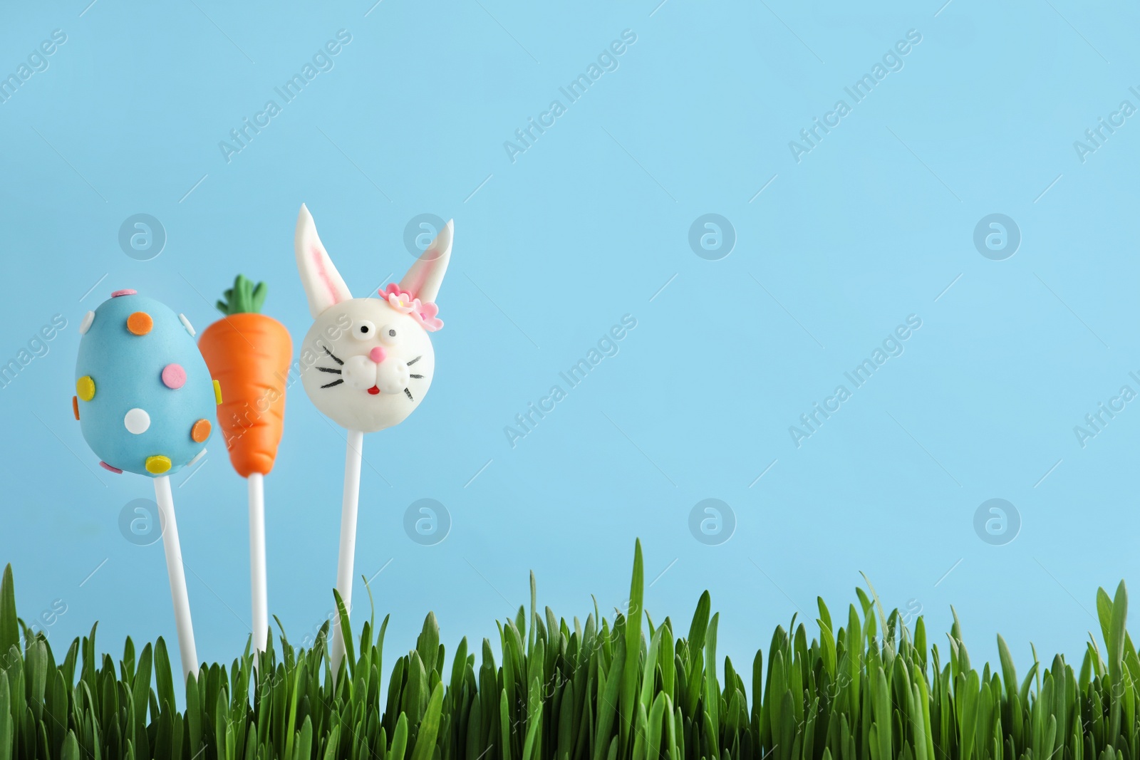 Photo of Different delicious sweet cake pops on light blue background, space for text. Easter holiday