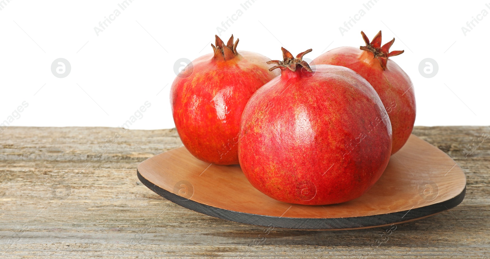 Photo of Fresh pomegranates on wooden table against white background