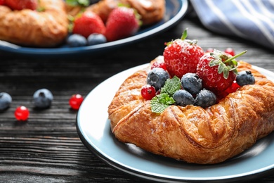 Photo of Fresh delicious puff pastry with sweet berries on dark wooden table