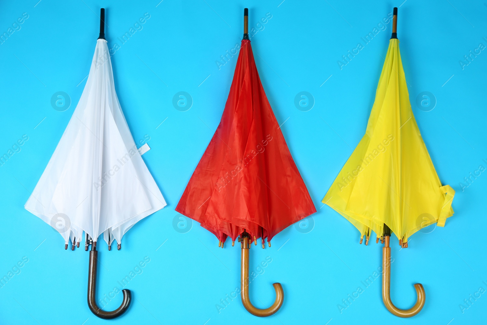 Photo of Beautiful colorful umbrellas on blue background, flat lay