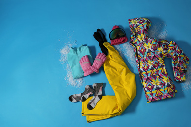 Stylish winter sport clothes on light blue background, flat lay