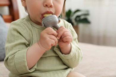 Photo of Baby girl with nibbler at home, closeup