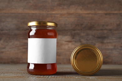 Photo of Jar of organic honey with blank label on wooden table. Space for text