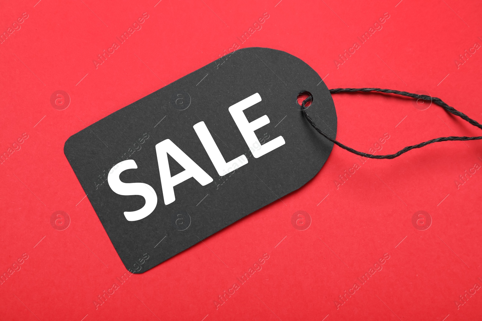 Photo of Sale tag on red background, top view. Black Friday