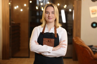 Photo of Portrait of professional hairdresser wearing apron in beauty salon