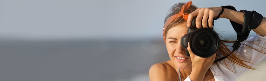 Image of Photographer taking photo with professional camera near sea, space for text. Banner design