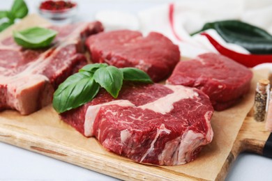 Photo of Cut fresh beef meat with basil leaves on wooden board, closeup