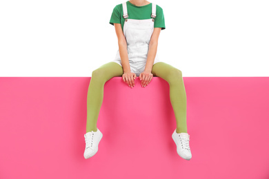 Woman wearing green tights and stylish shoes sitting on color background, closeup