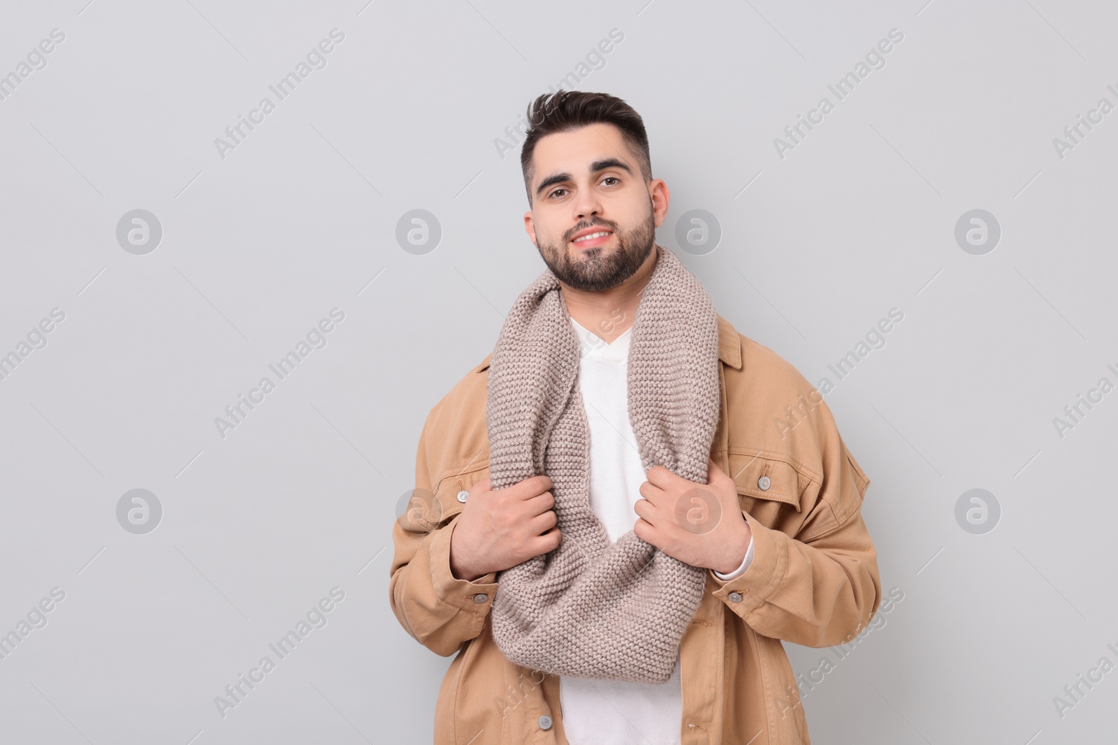 Photo of Smiling man in warm scarf on light grey background