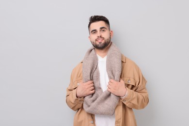 Smiling man in warm scarf on light grey background