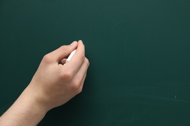 Teacher writing with chalk on green chalkboard, closeup. Space for text