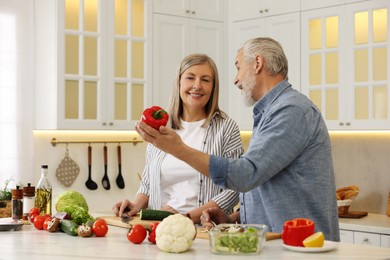 Happy senior couple cooking together in kitchen