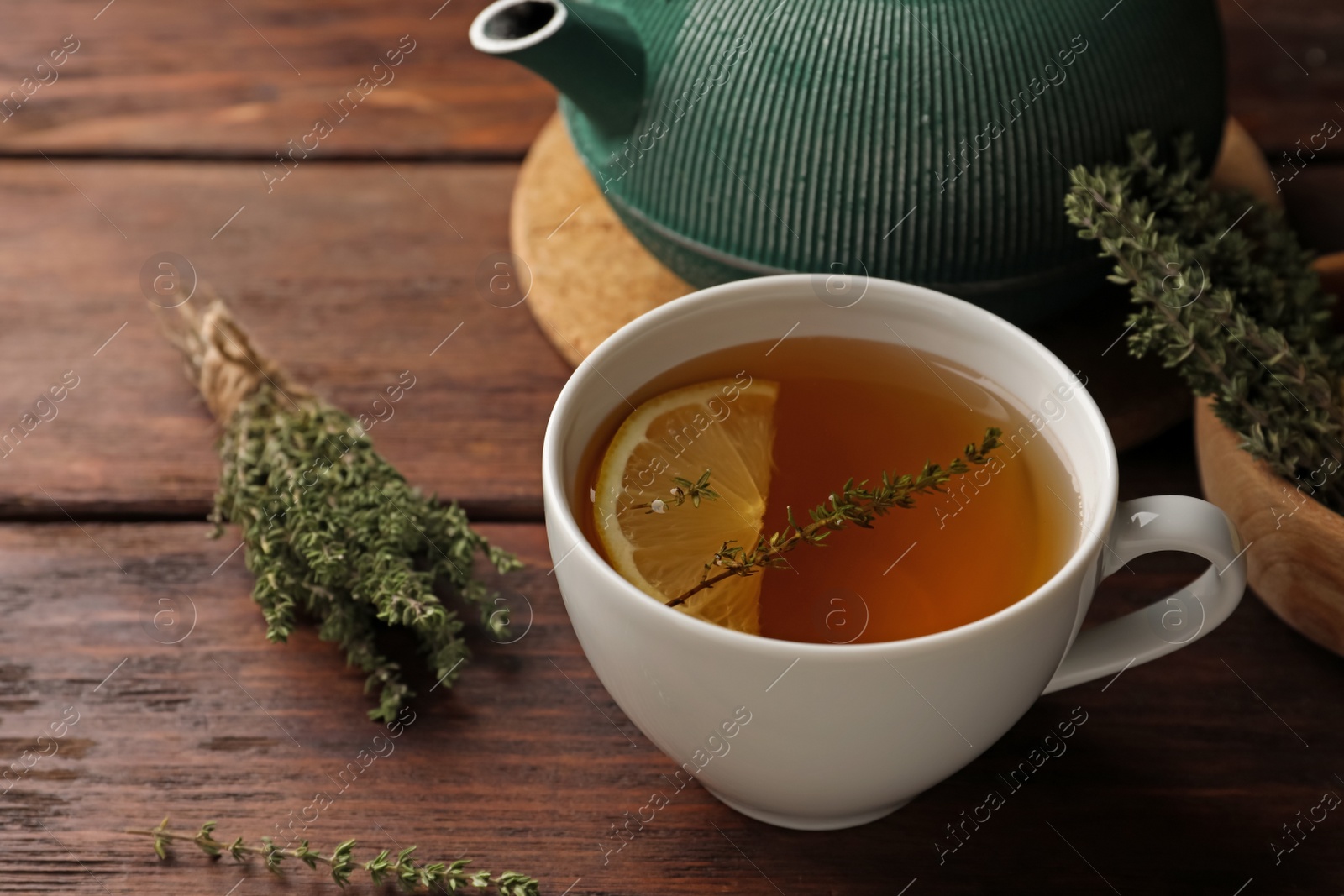 Photo of Aromatic herbal tea with thyme and lemon on wooden table