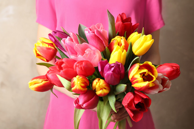 Woman holding beautiful spring tulips on light background, closeup