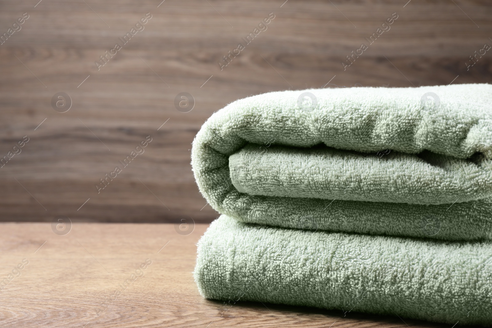 Photo of Folded soft towels on wooden table. Space for text