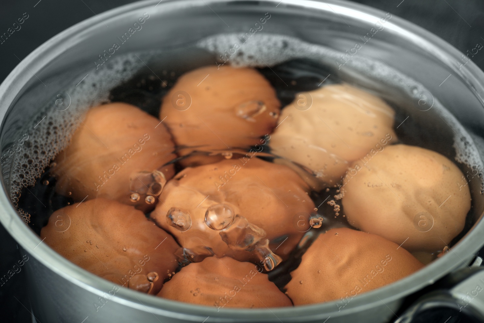Photo of Boiling chicken eggs in saucepan, closeup view
