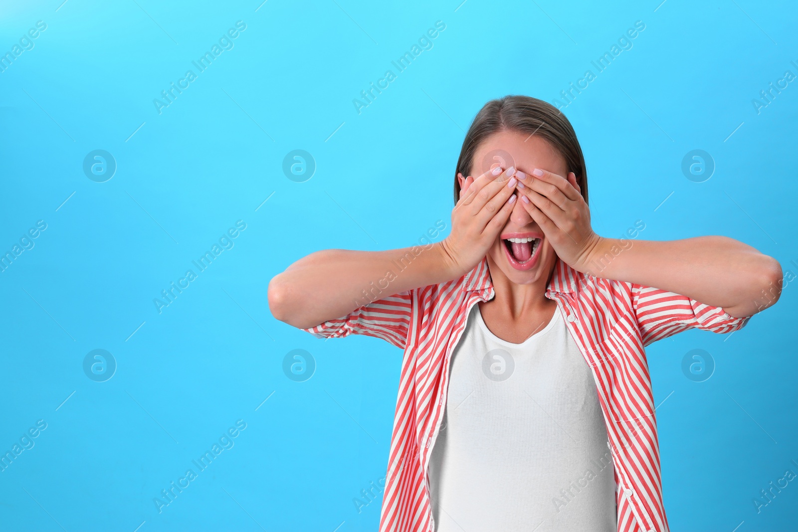 Photo of Young woman covering eyes with hands on blue background. Space for text