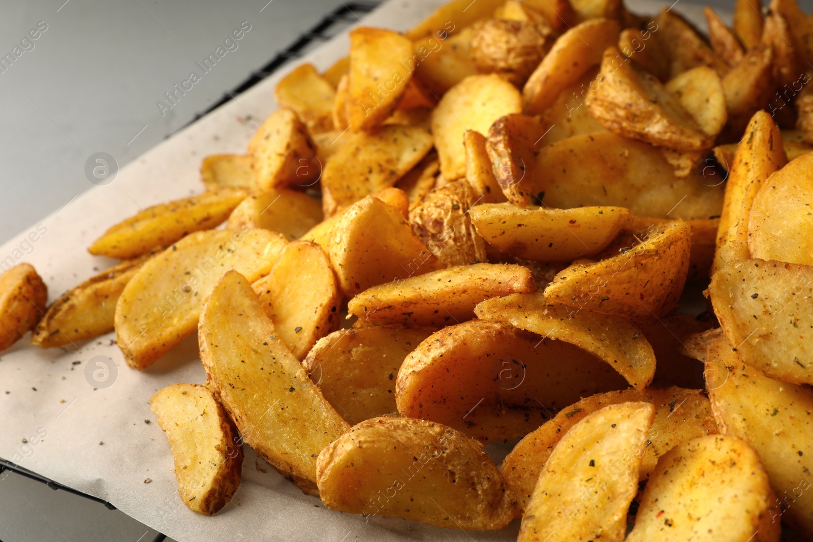 Photo of Delicious oven baked potatoes on parchment, closeup