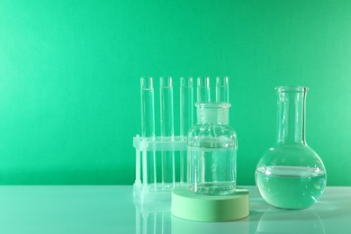 Photo of Laboratory analysis. Different glassware on table against green background, space for text