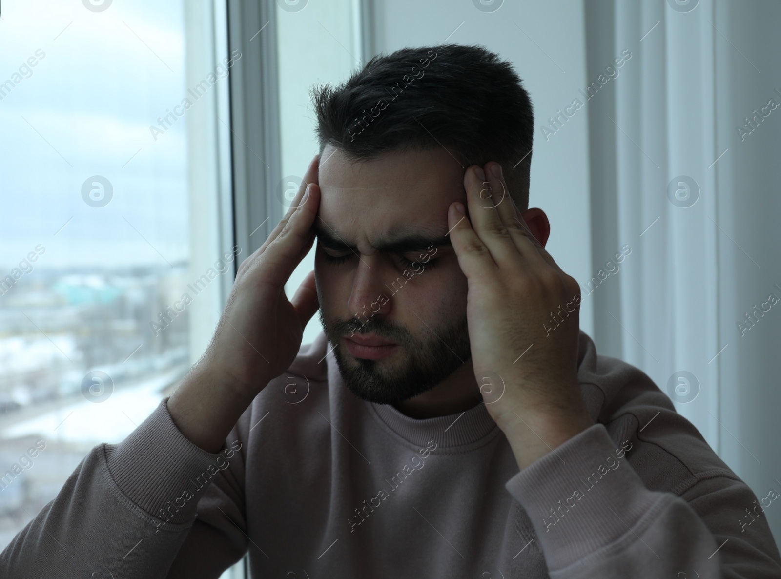 Photo of Portrait of sad man near window at home