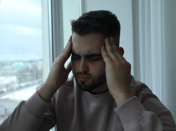 Portrait of sad man near window at home