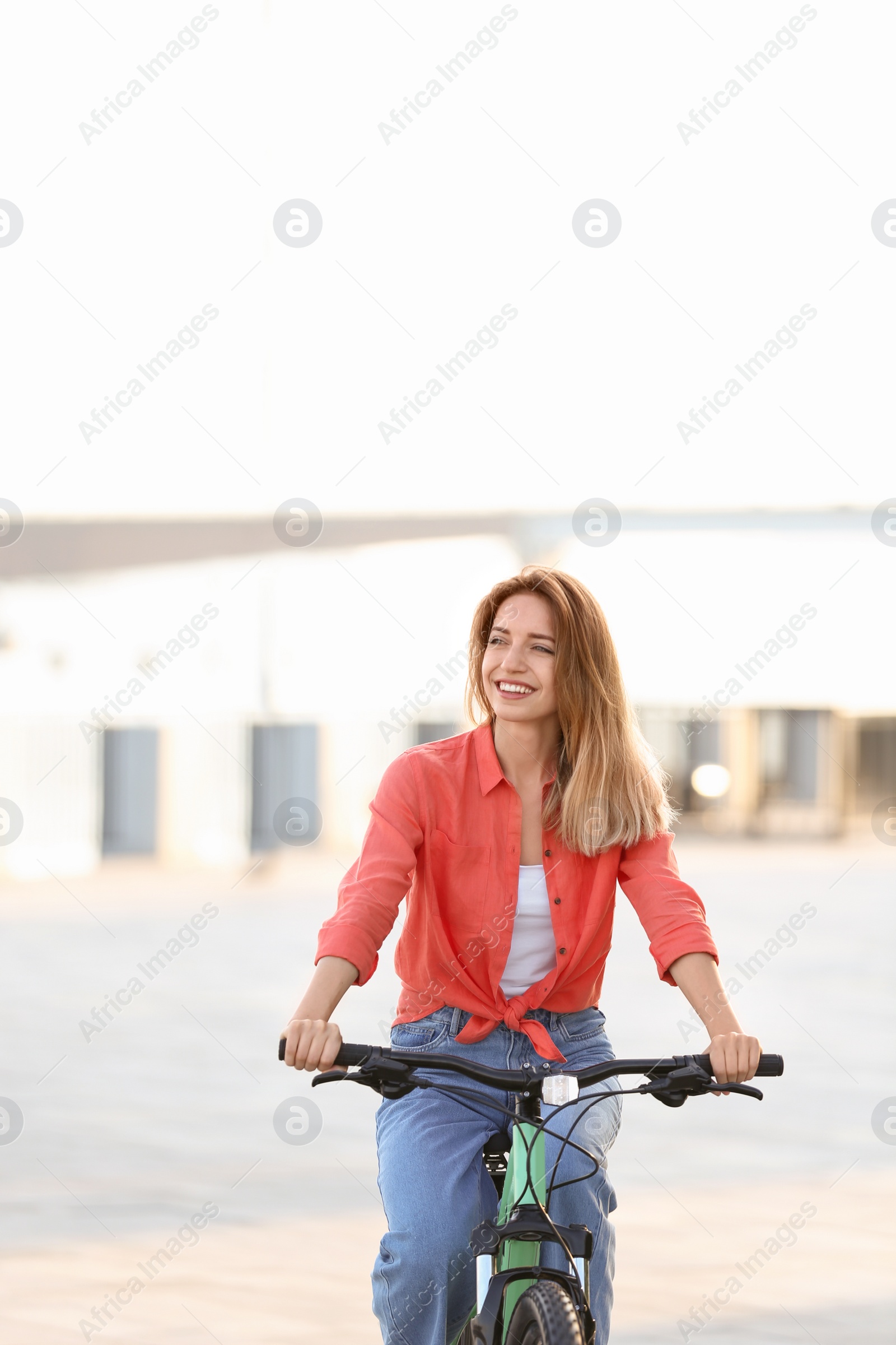 Photo of Young woman riding bicycle in city on sunny day