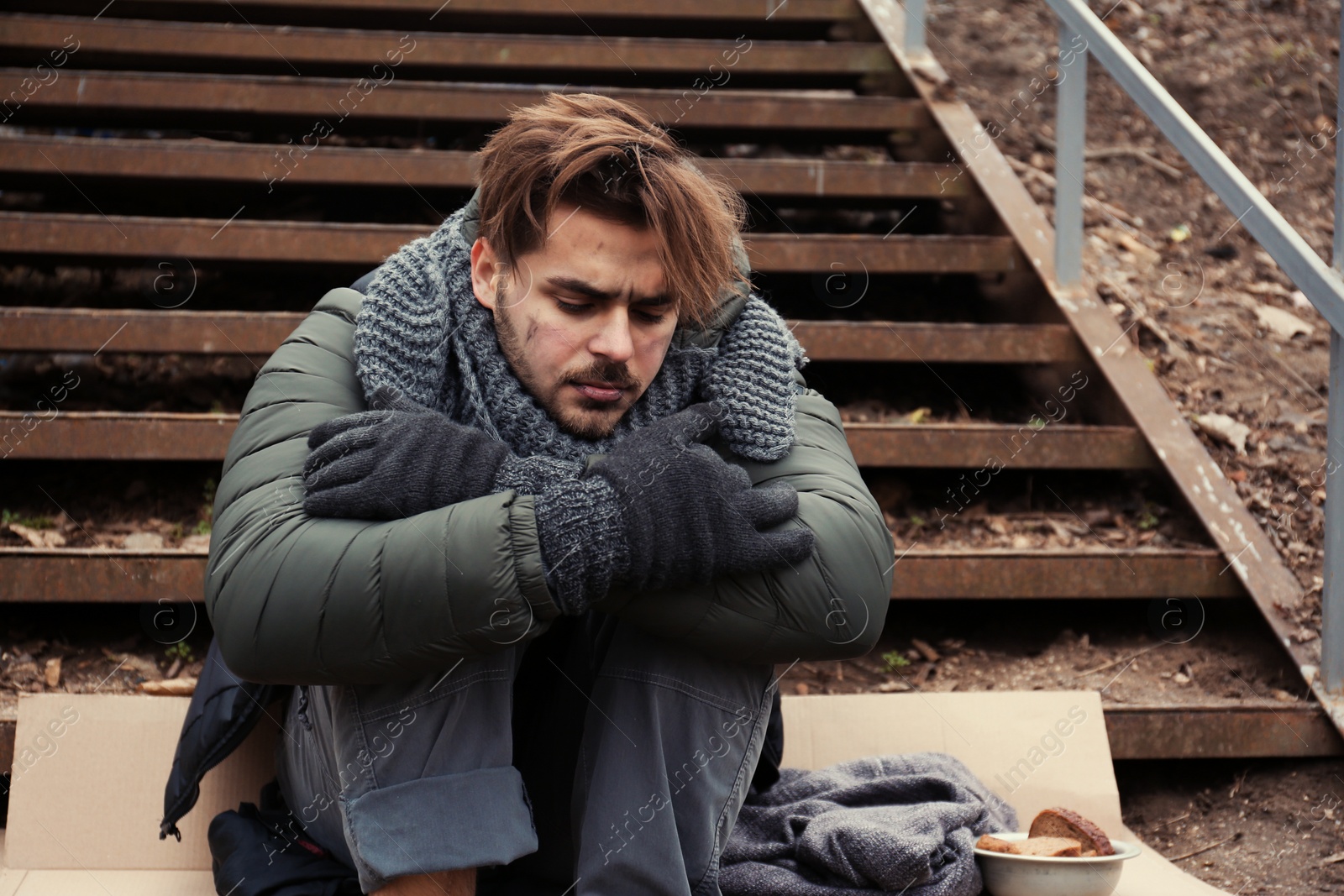 Photo of Poor young man sitting on stairs outdoors