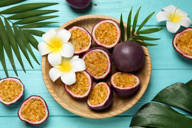 Photo of Passion fruits (maracuyas), flowers and green leaves on light blue wooden table, flat lay