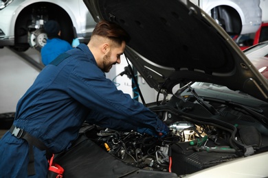 Technician checking modern car at automobile repair shop