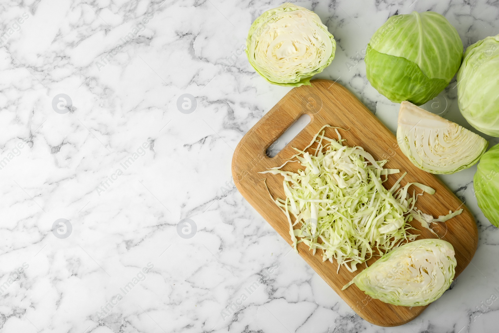 Photo of Chopped ripe cabbage on white marble table, flat lay. Space for text