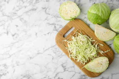 Photo of Chopped ripe cabbage on white marble table, flat lay. Space for text