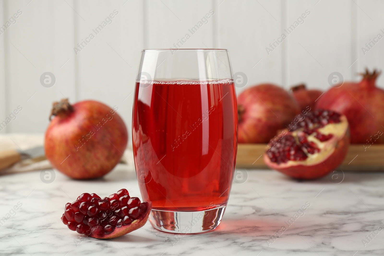 Photo of Tasty pomegranate juice in glass and fresh fruits on white marble table