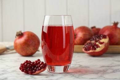 Photo of Tasty pomegranate juice in glass and fresh fruits on white marble table