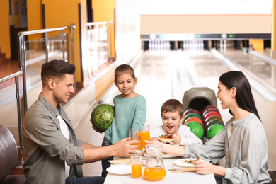 Photo of Happy family with pizza and drinks in bowling club