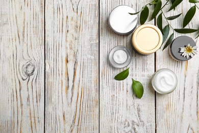 Photo of Composition with body cream in jars on wooden background, top view