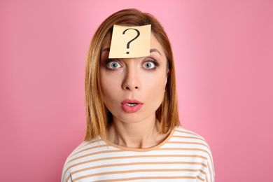 Photo of Emotional woman with question mark sticker on forehead against pink background