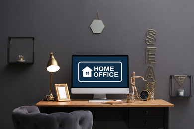 Image of Modern computer with text HOME OFFICE on table indoors