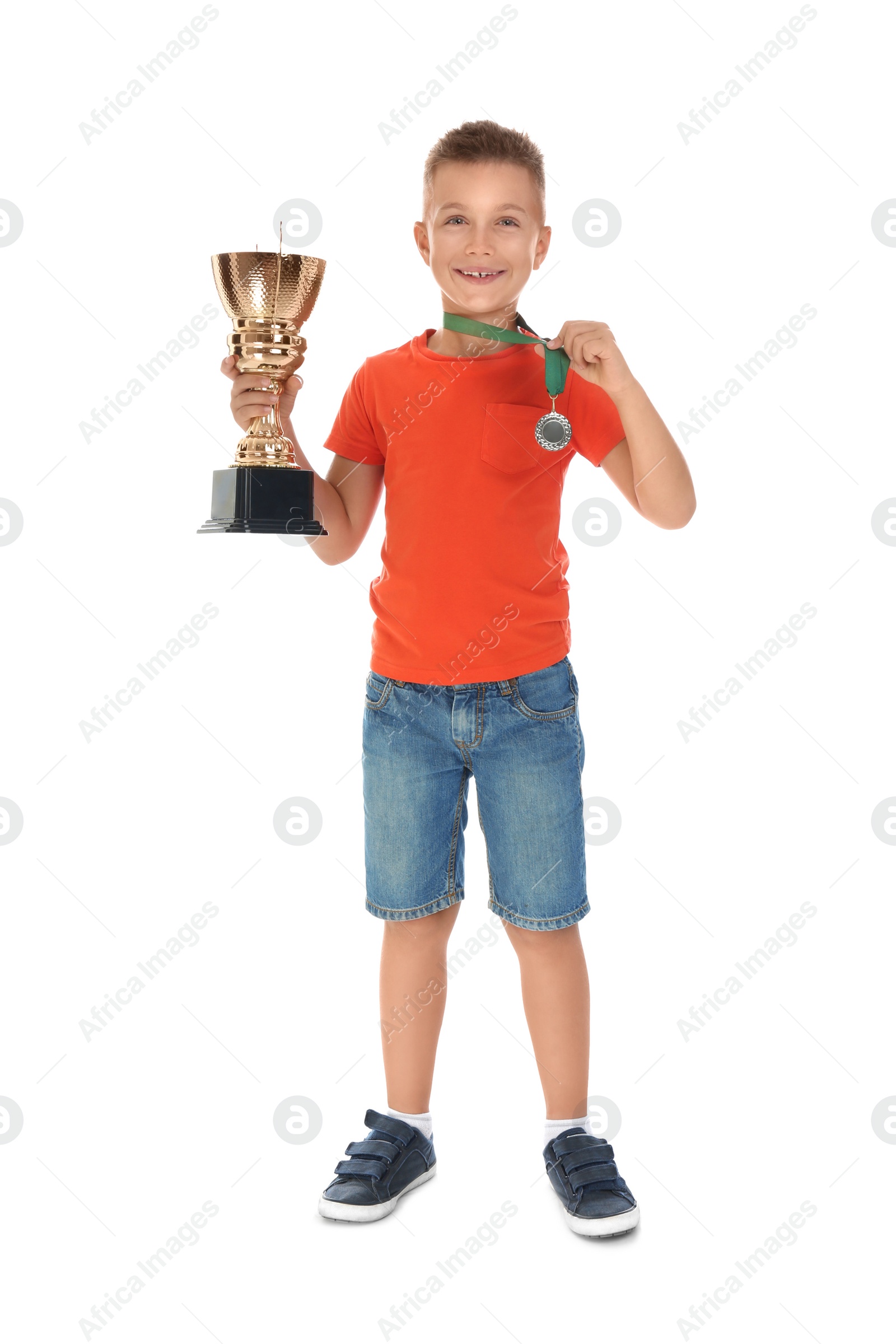 Photo of Happy boy with golden winning cup and medal isolated on white