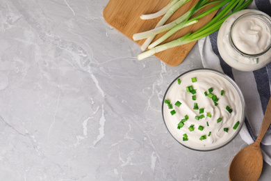 Fresh sour cream with onion on grey marble table, flat lay. Space for text